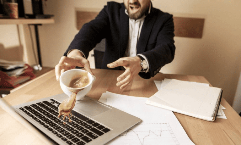 Distressed man spills coffee over MacBook keyboard